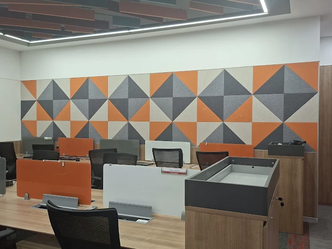 Geometric orange and charcoal acoustic wall panels in a modern office