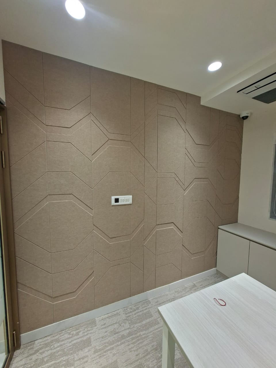 Beige acoustic wall panels with a subtle geometric pattern in a meeting room